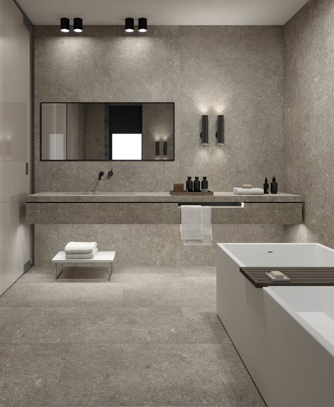 Bathroom lined in large grey porcelain tiles, with a floating vanity and bath